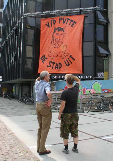 A squatter and the local mayor looking at the banner of V/D Putte.