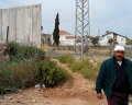 Hani Amer walking near the wall which runs next to his home in Mas'ha. Amer Madi