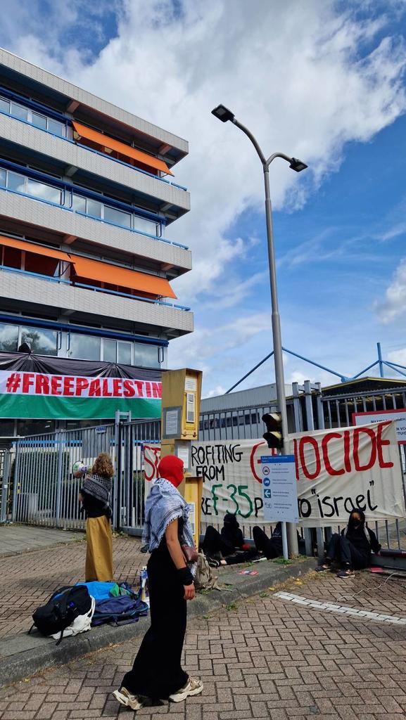 Activists blocking a gate with a huge Palestina flag hanging from Fokkers office